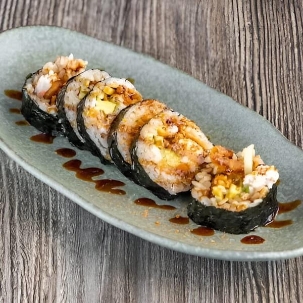 Five pieces of Izakaya Tora sushi rolls with sauce on a light green plate.